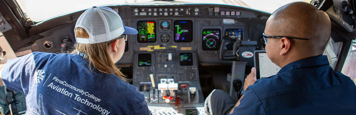 An Aviation student poses for a photo sitting on airplane at Pima's Aviation Center