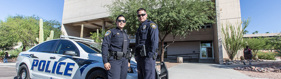 Two PCC police officers pose in front of their squad car