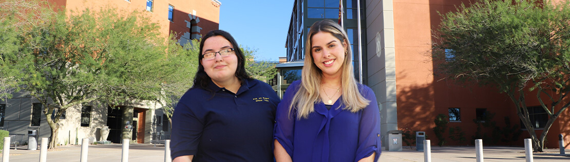 Pima’s Andrea Salazar Calderon and Halianna Piller stand smiling in front of Northwest Campus