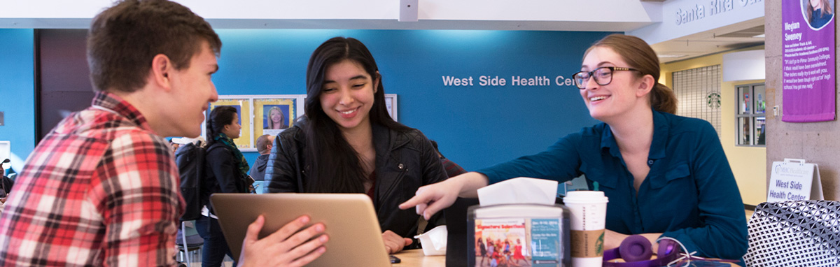 Three students look at a computer in a common student hall