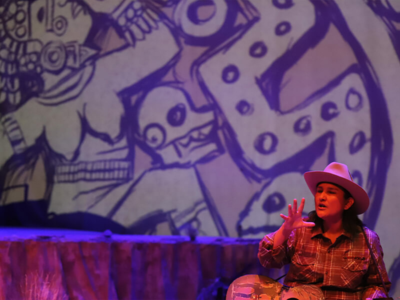 A scene from “Borderline” with Bridget Wilde’s Aztec-inspired illustration bringing the stage to life.