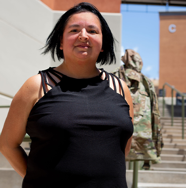 Angie Buenrostro stands smiling at Northwest Campus, her uniform in the background
