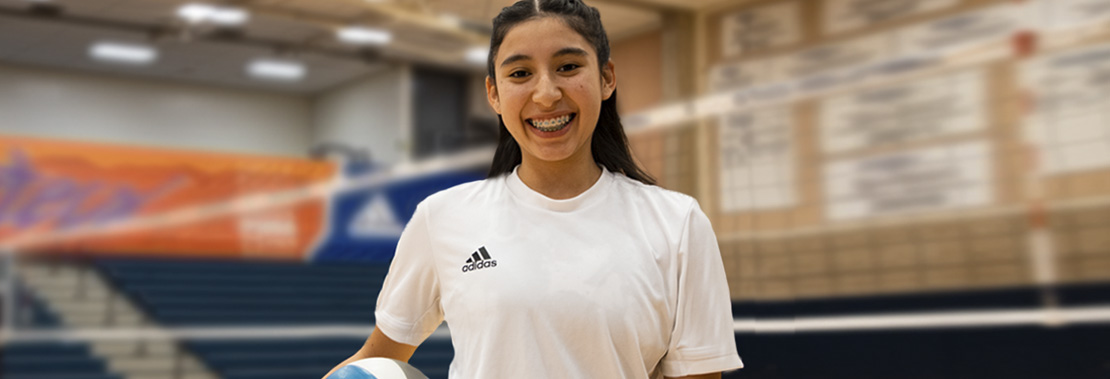 Karla Soto Smiles in front of a volleyball net in the West Campus Gym