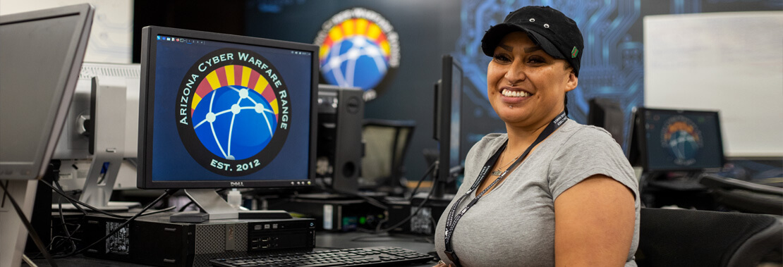 Aurora Sardina sits smiling in the Cyber Warfare Club room