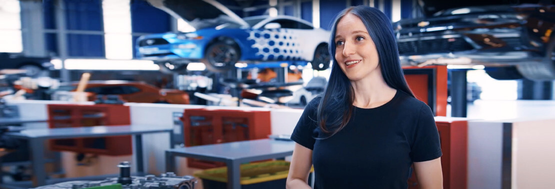 A female student stands smiling in the Automotive Industrial Building