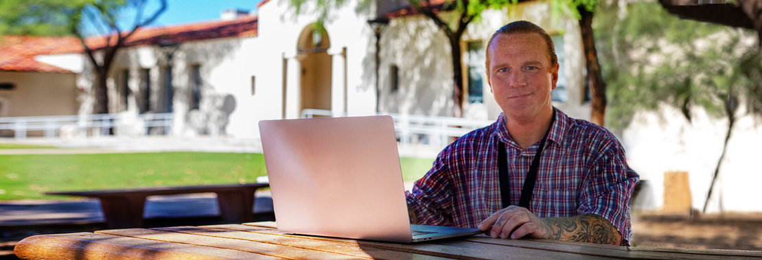 Peter Keith sitting at a desk outdoors