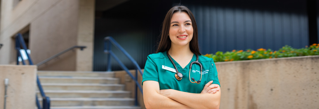 Lizbeth Mora stands smiling in scrubs at West Campus