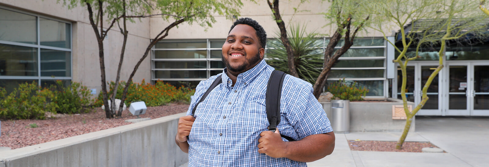Caleb Bailey stands smiling in front of Pima's West Campus