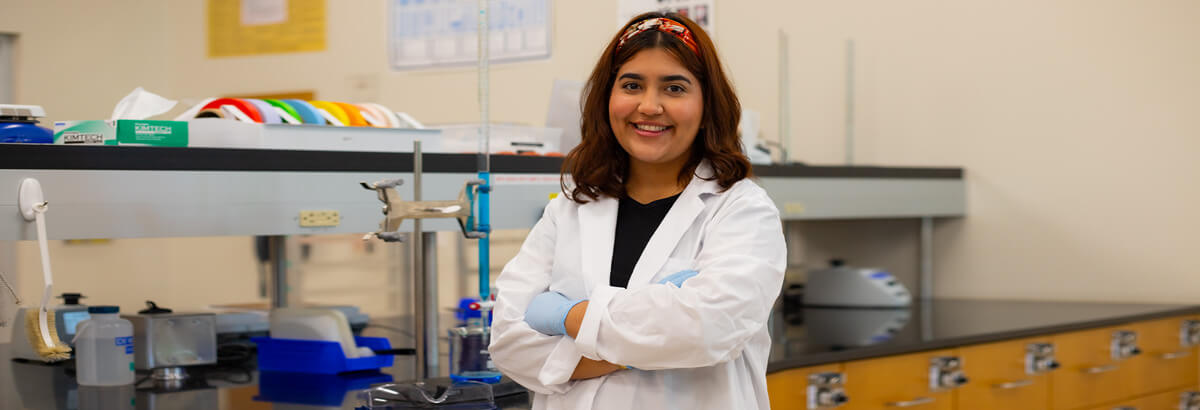 Marian Jimenez poses in front of a mural at Pima's Desert Vista Campus