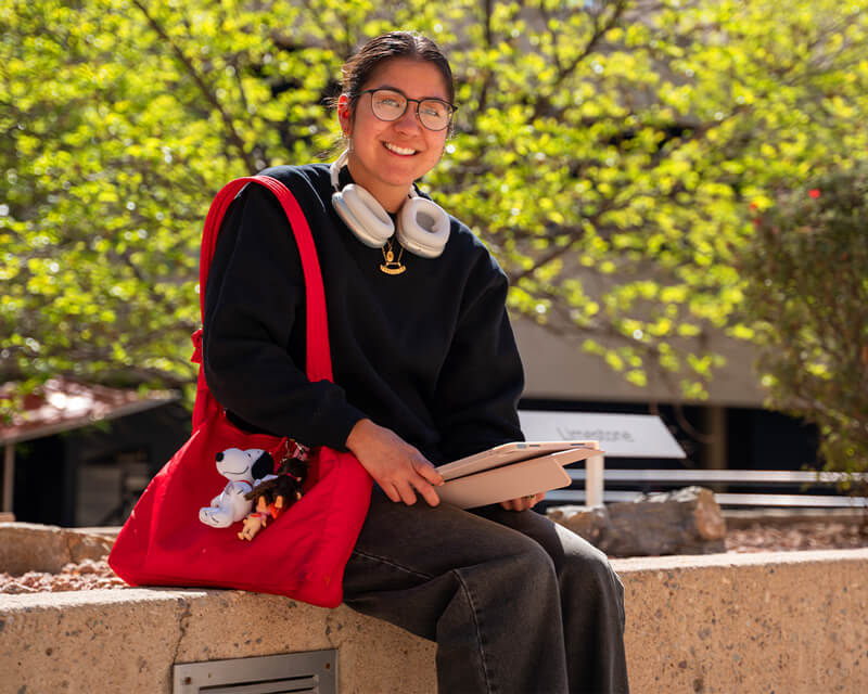 Student sitting on a parapet at west campus.
