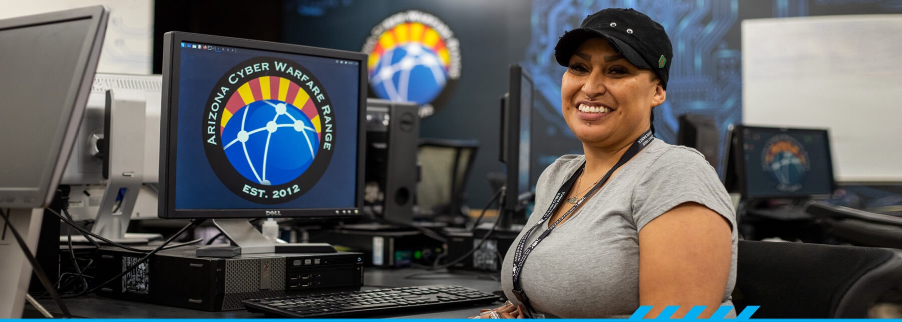 Aurora Sardina smiles for the camera while sitting at a computer terminal at the East Campus Center for Cybersecurity.