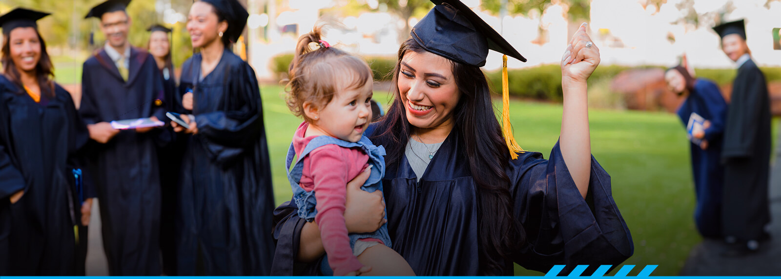 A parent-student holding their toddler during graduation. 