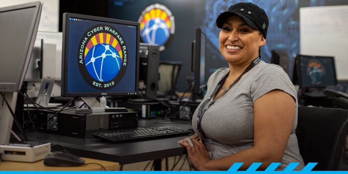 Aurora Sardina smiles for the camera while sitting at a computer terminal at the East Campus Center for Cybersecurity.