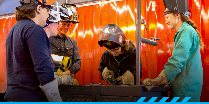 Regina Santaniello teaching students in a welding lab.