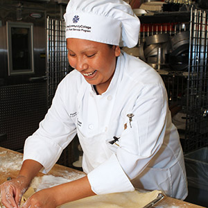 Pima Community College culinary program student wearing chef's jacket and working in kitchen