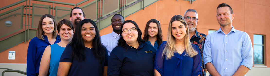 A group of diverse students and staff stand smiling at Northwest Campus