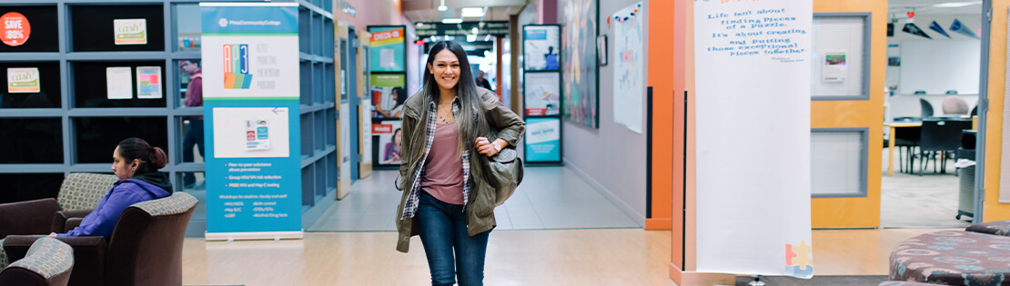 A student walks through the halls at Pima's Desert Vista Campus smiling