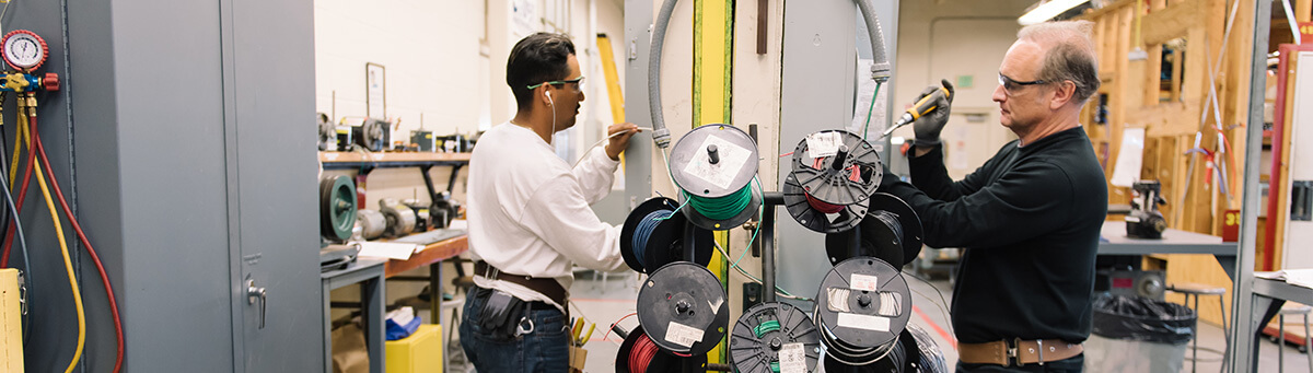 two students work on electrical equipment in a Pima Lab