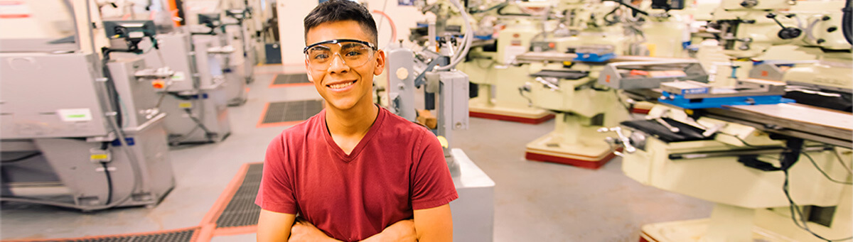 a student stands smiling in Pima's machine tooling class