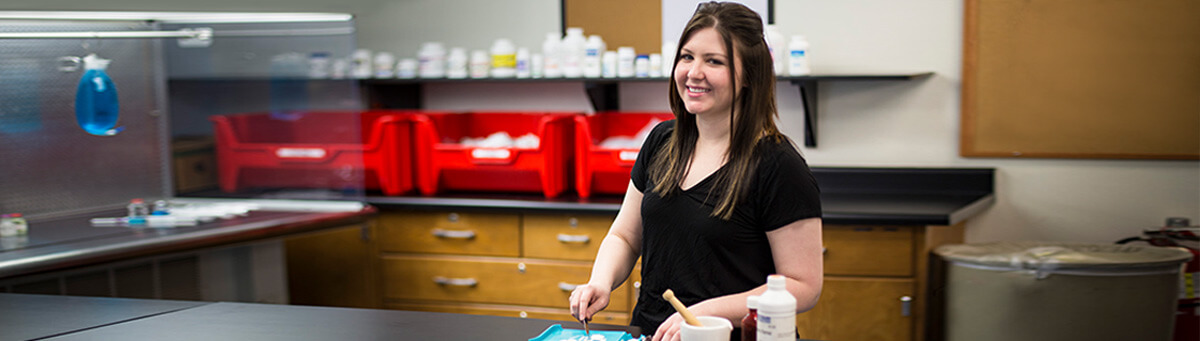 A student stands in front of a lab table in a Pima science lab