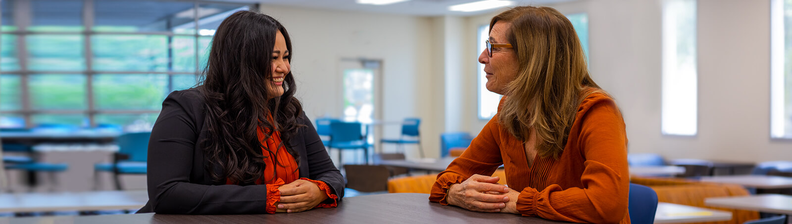 Two students sit smiling in a Pima campus student lounge