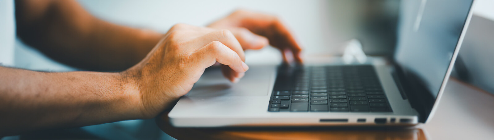 An incarcerated student writes on a computer up close