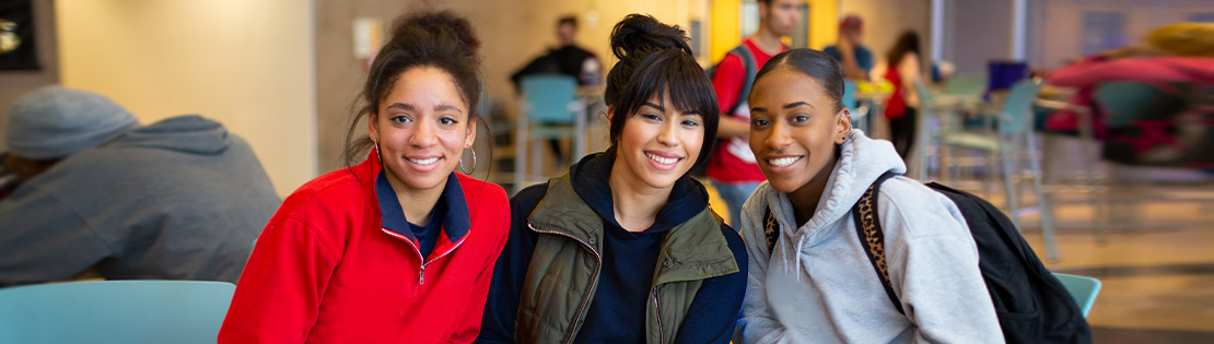 three students sit in a Pima Campus student lounge smiling 