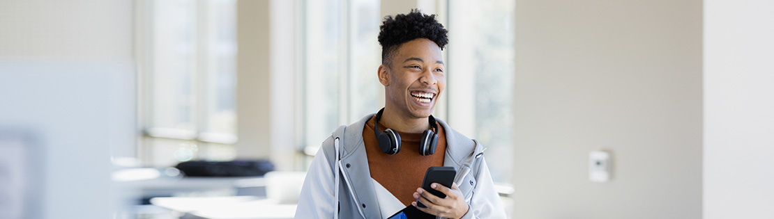 A student smiles while walking through school halls on his phone