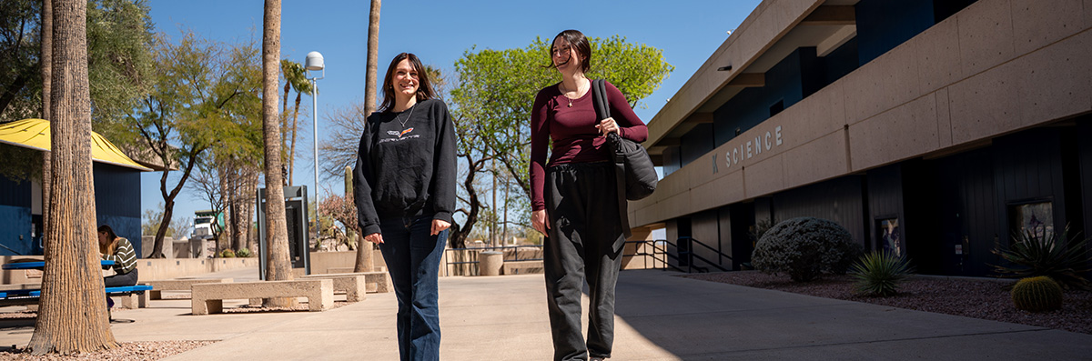 Two Pima Students walk in a West Campus breezeway