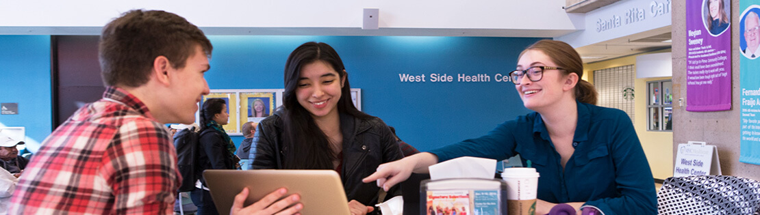 Students look at a computer and chat in a student lounge area