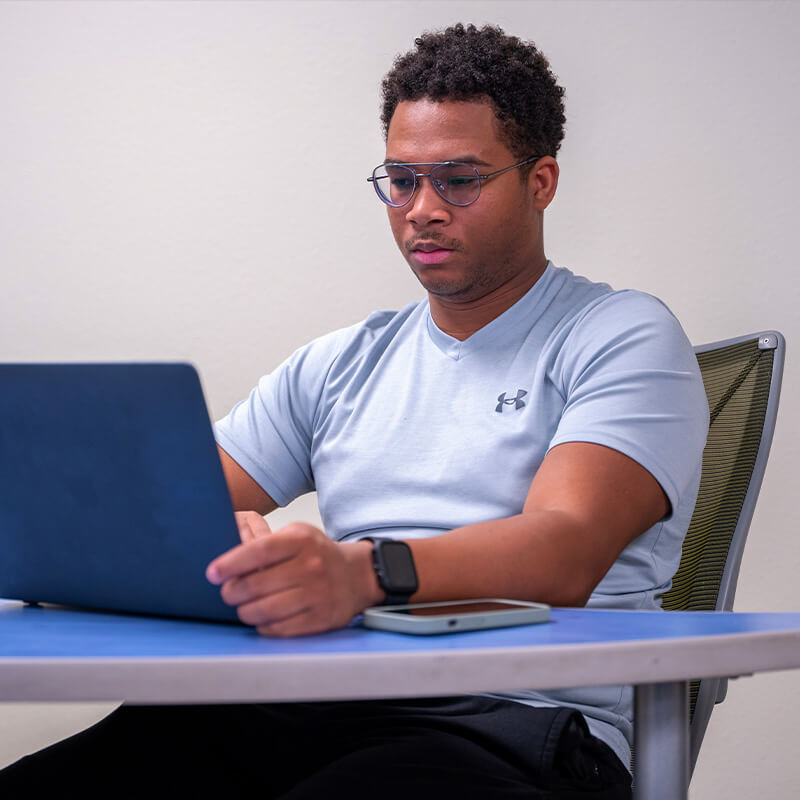 Khalil sits with a laptop in class