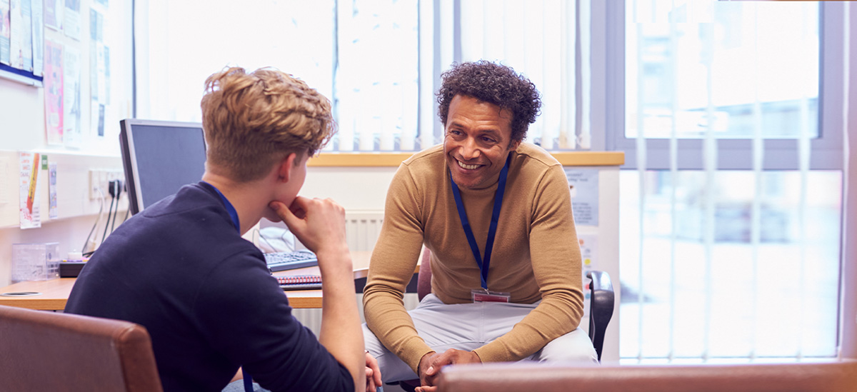 An advisor speaks to a student in his office